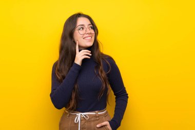 Izole sarı duvar üzerinde Genç kız bakarken bir fikir düşünme