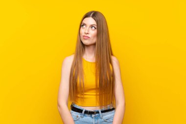 Izole sarı arka plan üzerinde genç kadın ayakta ve yan bakıyor