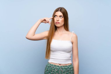 Izole mavi arka plan üzerinde genç kadın kafasına parmak koyarak delilik jest yapma