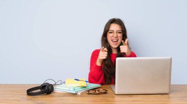 Genç öğrenci kız ön işaret eden bir masada okuyan ve gülümseyen