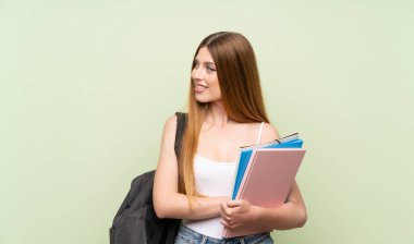 Izole yeşil arka plan üzerinde genç öğrenci kadın yan bakıyor