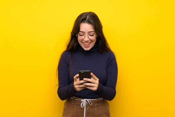 Tiener Meisje Geïsoleerde Gele Muur Een Bericht Verzenden Met Mobiele — Stockfoto