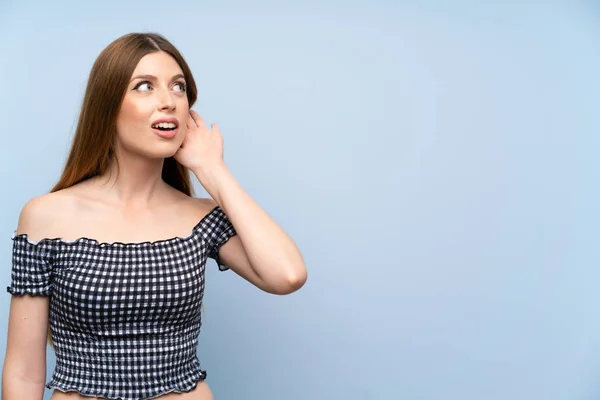 Mujer Joven Sobre Fondo Azul Aislado Escuchando Algo —  Fotos de Stock