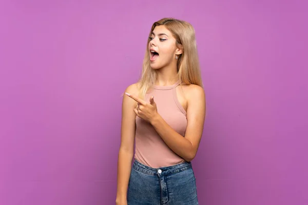 Adolescente Chica Sobre Aislado Púrpura Fondo Sorprendido Apuntando Lado —  Fotos de Stock