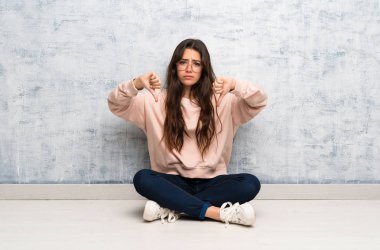 Bir tabloda okuyan genç öğrenci kız başparmak aşağı gösteren