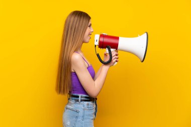 Izole sarı arka plan üzerinde genç kadın bir megafon ile bağırıyor