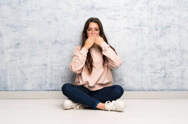 Genç öğrenci kız elleri ile ağız kapsayan bir masada okuyan