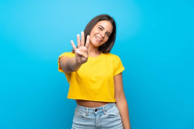 Izole mavi arka plan üzerinde genç kız mutlu ve parmakları ile dört sayma