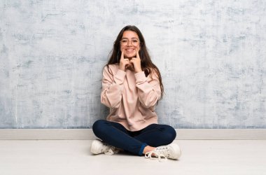 Genç öğrenci kız mutlu ve hoş bir ifade ile gülümseyerek bir masada okuyan