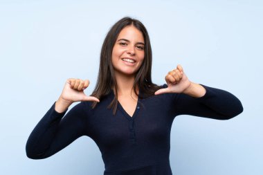 Izole mavi arka plan üzerinde Genç kız gururlu ve kendini tatmin