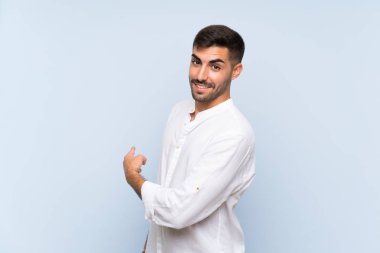 Izole mavi arka plan üzerinde sakallı yakışıklı adam geri işaret