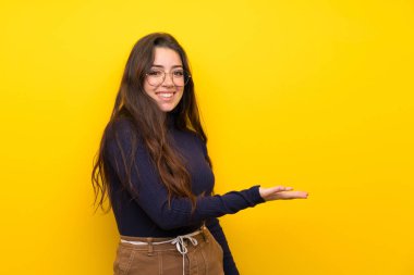 Doğru gülümseyerek bakarken izole sarı duvar üzerinde genç kız bir fikir sunan