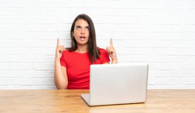 İşaret parmağı ile işaret eden bir masada pc ile genç kız harika bir fikir