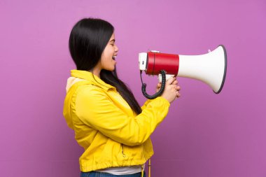Bir megafon ile bağırarak izole mor arka plan üzerinde genç genç Asyalı kız