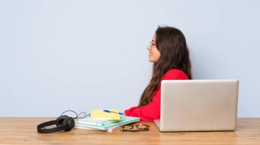 Yanal pozisyonda bir masada okuyan genç öğrenci kız