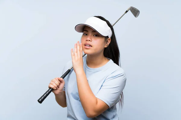 孤立した青い背景の上に若いゴルファーアジアの女の子が何かをささやく — ストック写真