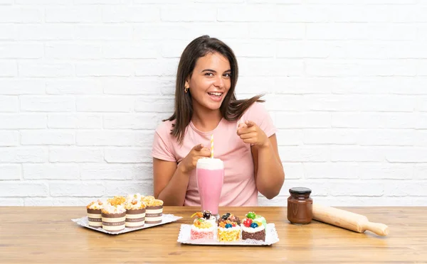 Junges Mädchen Mit Vielen Verschiedenen Mini Kuchen Zeigt Mit Dem — Stockfoto