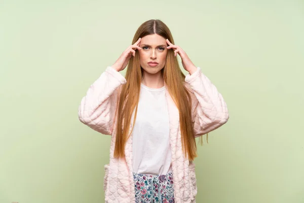 Young woman in dressing gown over green wall unhappy and frustrated with something. Negative facial expression