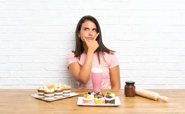 Junges Mädchen Mit Vielen Verschiedenen Mini Kuchen Denkt Sich Eine — Stockfoto