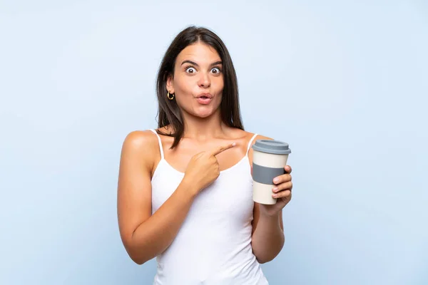 파란색 배경에 커피를 가라가 여성이 측면을 가리킵니다 — 스톡 사진