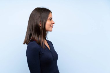 Izole mavi arka plan üzerinde genç kız yan bakıyor