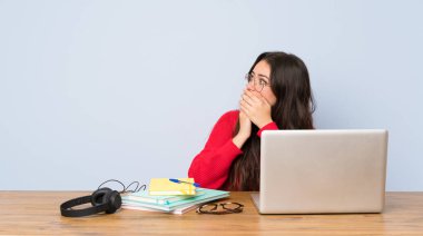 Genç öğrenci kız ağız kapsayan bir masada okuyan ve yan bakıyor