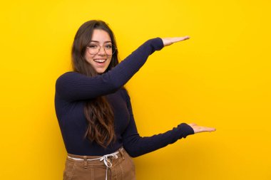 Bir reklam eklemek için copyspace tutan izole sarı duvar üzerinde Genç kız