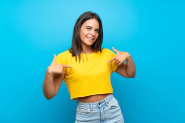 Izole mavi arka plan üzerinde Genç kız gururlu ve kendini tatmin