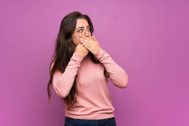 Genç kız ağız kapsayan ve tarafına bakarak mor duvar üzerinde