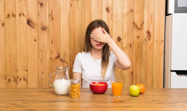 Genç sarışın kadın elleriyle gözleri kaplayan kahvaltı sahip