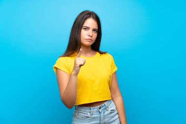 Izole mavi arka plan üzerinde Genç kız sinirli ve ön işaret