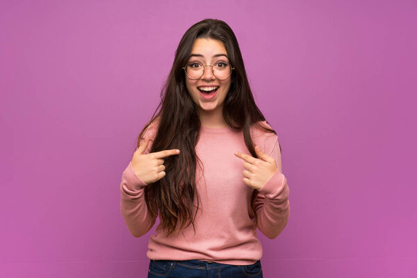 Teenager girl over purple wall with surprise facial expression