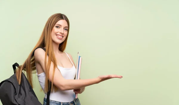 Joven Estudiante Sobre Fondo Verde Aislado Extendiendo Las Manos Lado —  Fotos de Stock