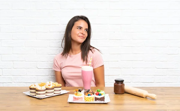 Junges Mädchen Mit Vielen Verschiedenen Mini Kuchen Lachend Und Aufblickend — Stockfoto