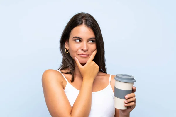 Mladá Žena Která Odbere Kávu Přes Izolované Modré Pozadí Uvažuje — Stock fotografie