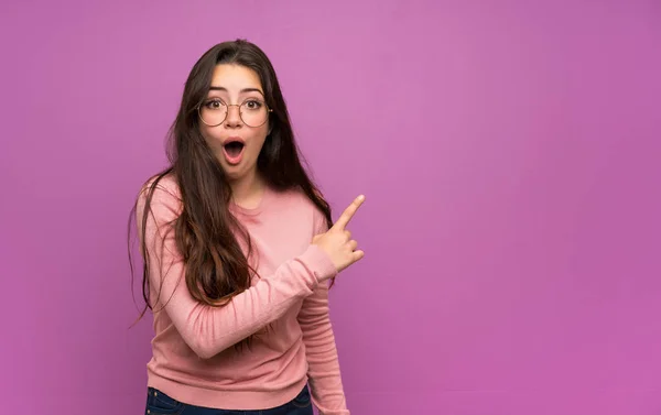 Menina Adolescente Sobre Parede Roxa Surpreendido Apontando Lado — Fotografia de Stock