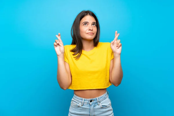 Menina Sobre Fundo Azul Isolado Com Dedos Cruzando Desejando Melhor — Fotografia de Stock