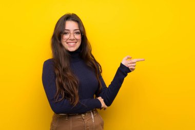 Izole sarı duvar tarafında parmak işaret üzerinde Genç kız