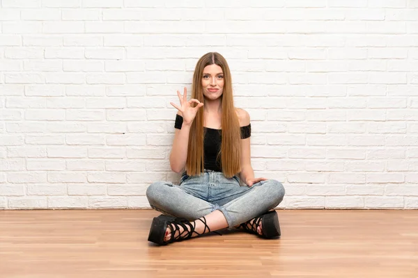 Mujer Joven Sentada Suelo Mostrando Signo Con Los Dedos —  Fotos de Stock
