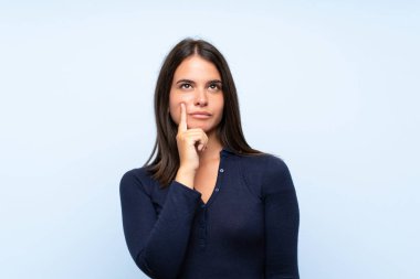 Izole mavi arka plan üzerinde genç kız bir fikir düşünme