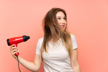 Saç kurutma makinesi ile pembe arka plan üzerinde Genç kız