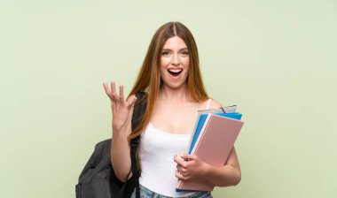 Izole yeşil arka plan üzerinde genç öğrenci kadın mutsuz ve bir şey ile sinirli