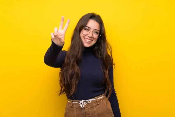 Adolescente Chica Sobre Aislada Pared Amarilla Sonriendo Mostrando Signo Victoria —  Fotos de Stock