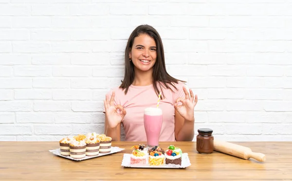 Chica Joven Con Montón Diferentes Mini Pasteles Que Muestran Signo — Foto de Stock