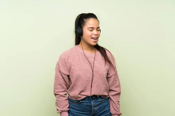 Jonge Tiener Aziatische Meisje Geïsoleerde Groene Achtergrond Luisteren Naar Muziek — Stockfoto