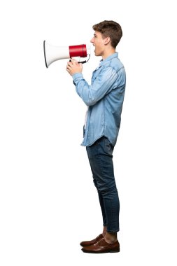 İzole beyaz arka plan üzerinde bir megafon ile bağıran yakışıklı bir genç adam tam uzunlukta bir çekim