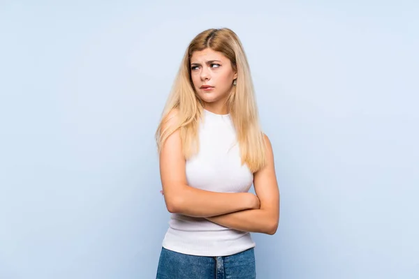 Tenåringsjente Med Isolert Blå Bakgrunn Som Sender Melding Med Mobiltelefonen – stockfoto