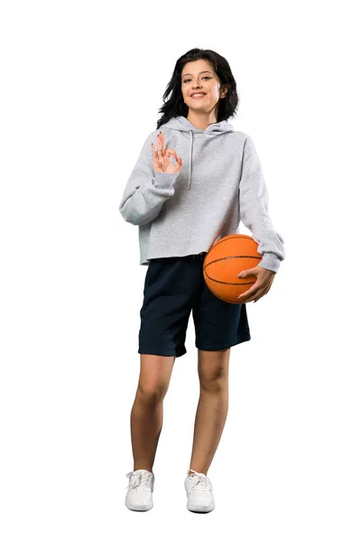 一个年轻女子打篮球的全长镜头显示 用手指在孤立的白色背景上显示好标志 — 图库照片