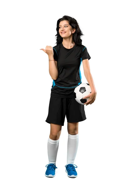 一个年轻足球运动员妇女指着侧面在孤立的白色背景上展示产品的全长镜头 — 图库照片