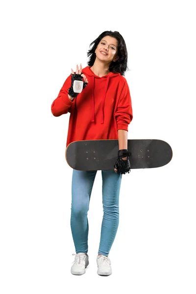 孤立した白い背景の上に指でOkサインを示す若いスケーターの女性のフルレングスショット — ストック写真